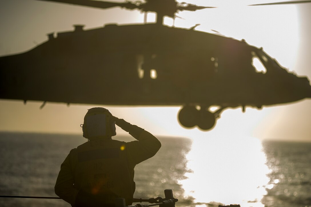 Navy Petty Officer 3rd Class Bryan Duncan salutes an MH-60S Seahawk helicopter from the flight deck of the USS Gonzalez in the Gulf of Aden, April 23, 2016. The Gonzalez is deployed as part of the Harry S. Truman Carrier Strike Group to support Operation Inherent Resolve and other security efforts in the U.S. 5th Fleet area of responsibility. Navy photo by Petty Officer 3rd Class Pasquale Sena