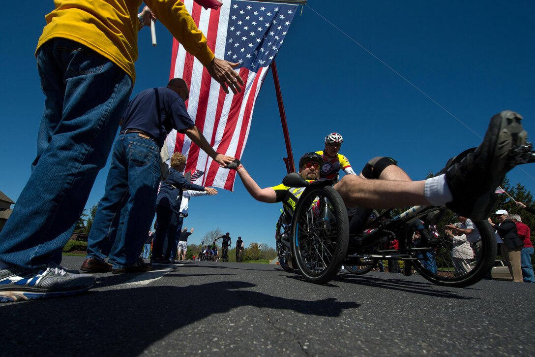 Former Navy Petty Officer 1st Class Jay Somers, right, gives high-fives as he passes through a cheering crowd along the Face of America bike route in Gettysburg, Pa., April 24, 2016. DoD photo by EJ Hersom