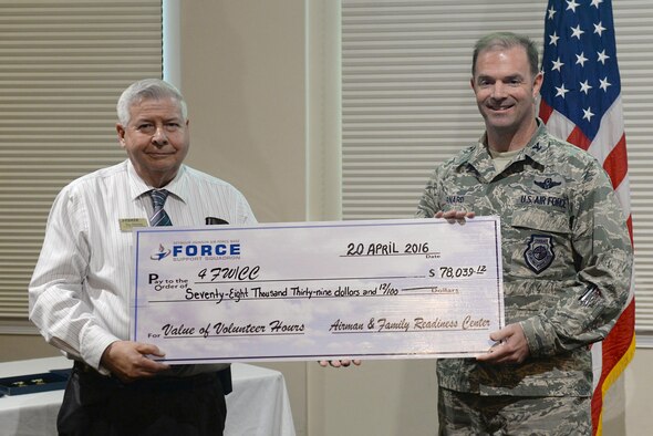 Ray Ramsey, 4th Force Support Squadron volunteer program manager, presents a check to the 4th Fighter Wing, accepted by Col. Andrew Bernard, 4th FW vice commander, April 20, 2016, at Seymour Johnson Air Force Base, North Carolina. The check symbolized the value of volunteer hours contributed by 4th FW Airmen over the past 12 months. (U.S. Air Force photo by Airman 1st Class Ashley Williamson/Released)