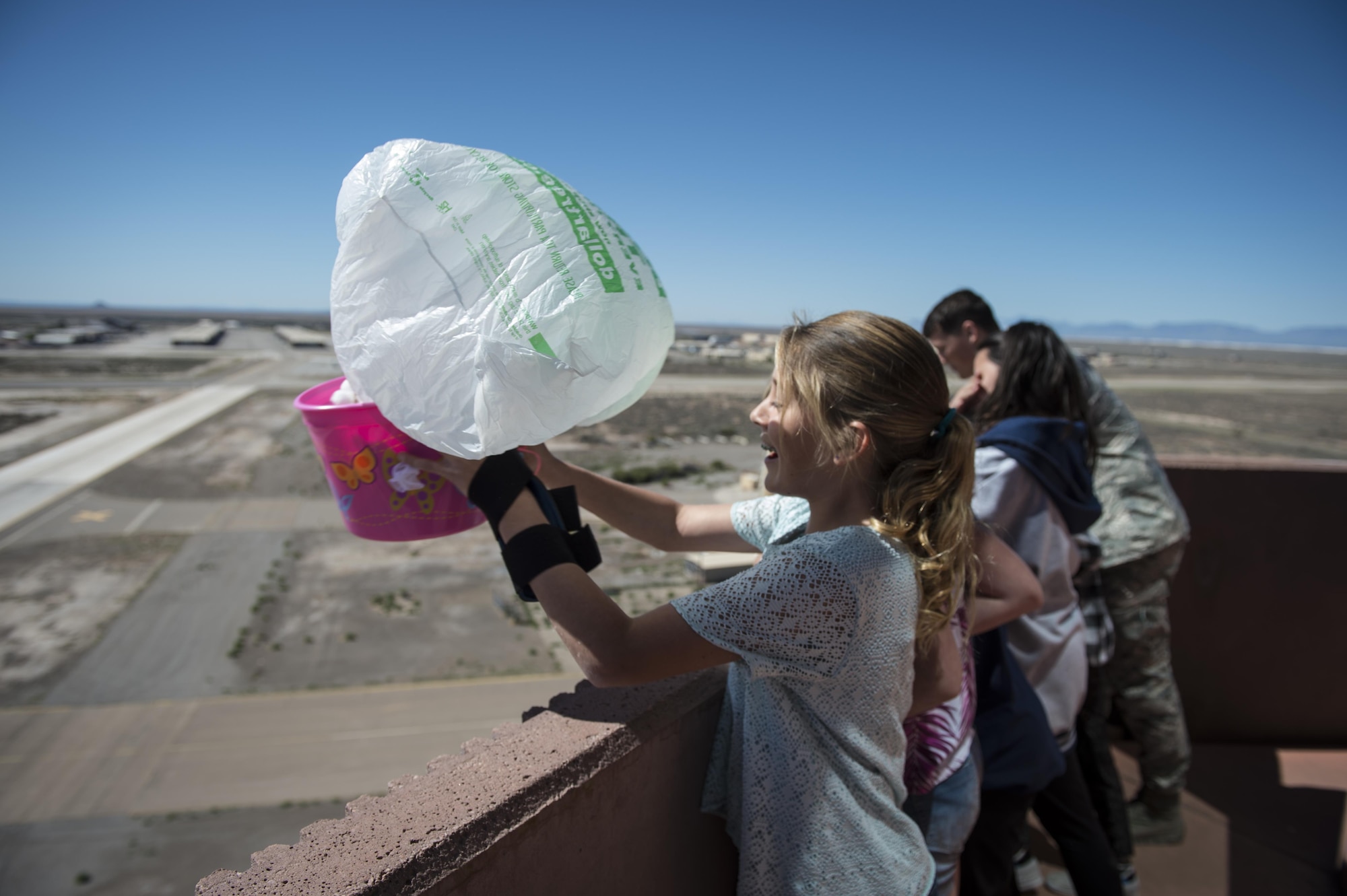A student from Holloman Elementary School prepares to drop a protected egg as part of Holloman Egg Drop Science Project at the Holloman Air Force Base air traffic control tower here, April 14. The egg drop project challenges students to create a contraption that will keep an egg safe from impact after being dropped from a tall building, in this case, 14 stories. Typically eggs are dropped from the participating school’s roof. Holloman students had the unique opportunity to utilize the air traffic control tower for this project. (U.S. Air Force photo by Senior Airman BreeAnn Sachs)