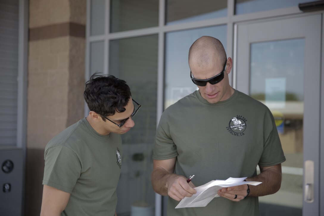 Seaman Marcus Cruz, hospital corpsman, and Petty Officer 3rd Class Mike Gerasimovich, physical therapist, Robert E. Bush Naval Hospital, look at clues leading to the next location outside of the Education Center during the Substance Abuse Program’s Scavenger Hunt April 15, 2016. (Official Marine Corps photo by Pfc. Dave Flores/Released)