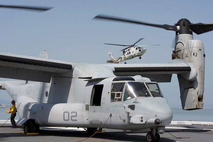 YATSUSHIRO BAY, Japan (April 22, 2016) An MV-22B Osprey from Marine Medium Tiltrotor Squadron (VMM) 265 (Reinforced) attached to the 31st Marine Expeditionary Unit is loaded with relief supplies as an SH-60K Sea Hawk helicopter from the Japan Maritime Self-Defense Force takes off from the destroyer helicopter ship JS Hyuga (DDH) 181. At request of the Japanese government, U.S. Forces Japan is providing airlift support to Japanese Self-Defense Forces (JSDF). A JSDF task force of more than 25,000 personnel is providing humanitarian and disaster relief assistance to the people affected by the magnitude 6.5 and 7.3 earthquakes that struck the Kumamoto area on 14 and 16 April 2016. 
