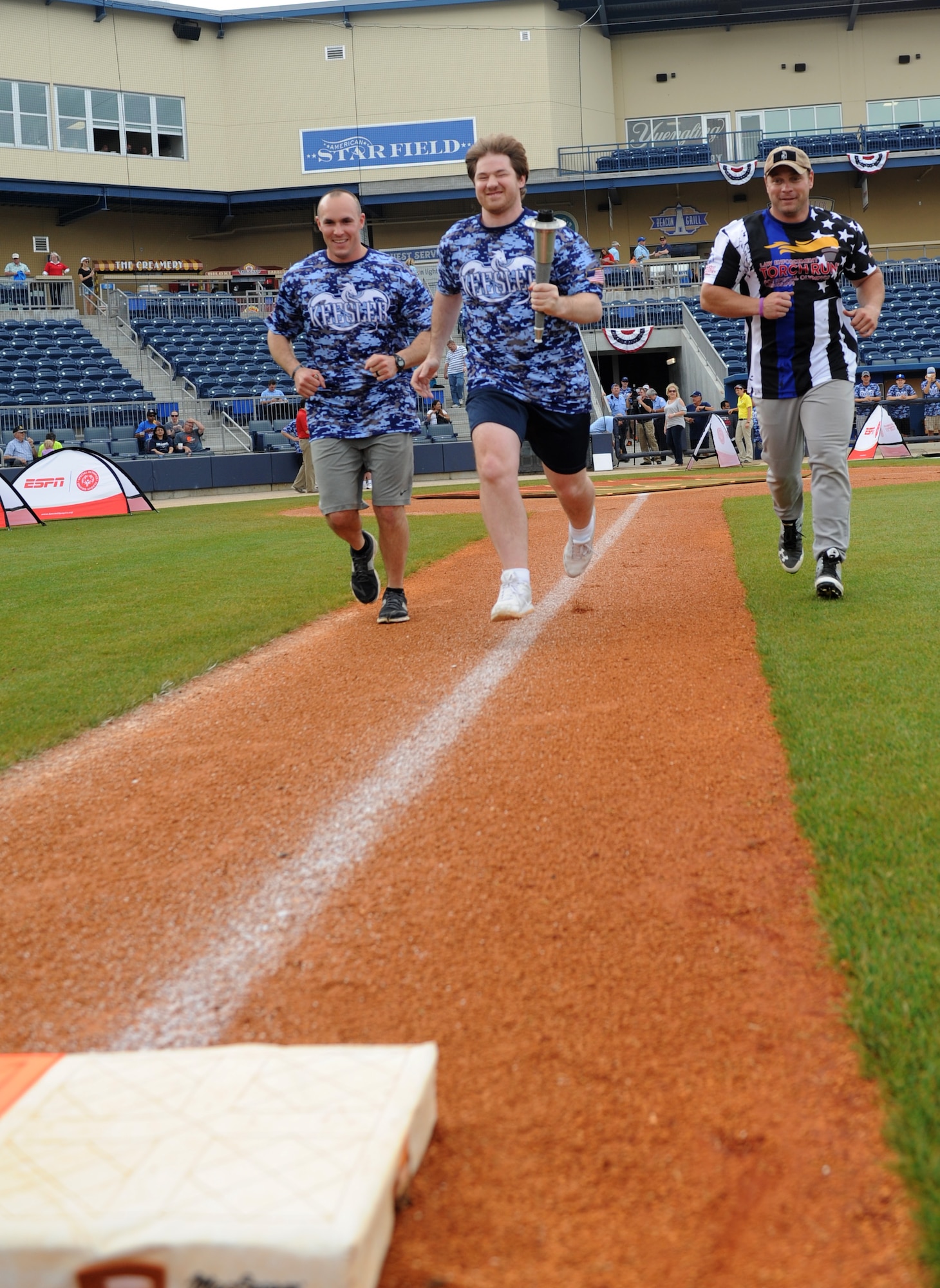 Capt. Harlan Glinski, 81st Security Forces operations officer and “Boots” team member; Lee Brown, Special Olympics athlete; and Doug DeGeorge, Biloxi Police Department police officer and “Badges” team member, participate in the torch run around the baseball field during the “Boots versus Badges” softball game at the Biloxi Shuckers MGM Park April 21, 2016, Biloxi, Miss. The game was the kickoff event for the 2016 Special Olympics Mississippi Summer Games, which will be hosted by Keesler Air Force Base, Miss., May 20-21. (U.S. Air Force photo by Kemberly Groue)
