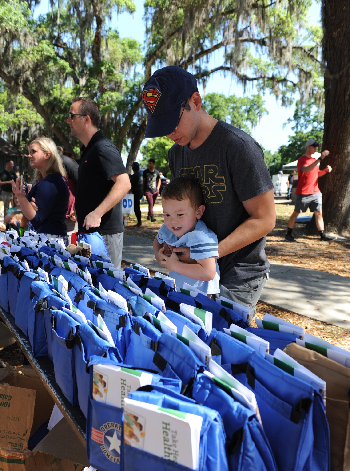 Tech. Sgt. Albert Cortez, 81st Diagnostic and Therapeutics Squadron radiology technician, helps his son, Alex, grab a goody bag during Child Pride Day at marina park April 23, 2016, Keesler Air Force Base, Miss. Keesler families attended the annual event which featured activities, demonstrations and information on programs focused on care of military families. Child Pride Day was held in conjunction with the month of the military child. (U.S. Air Force photo by Kemberly Groue)