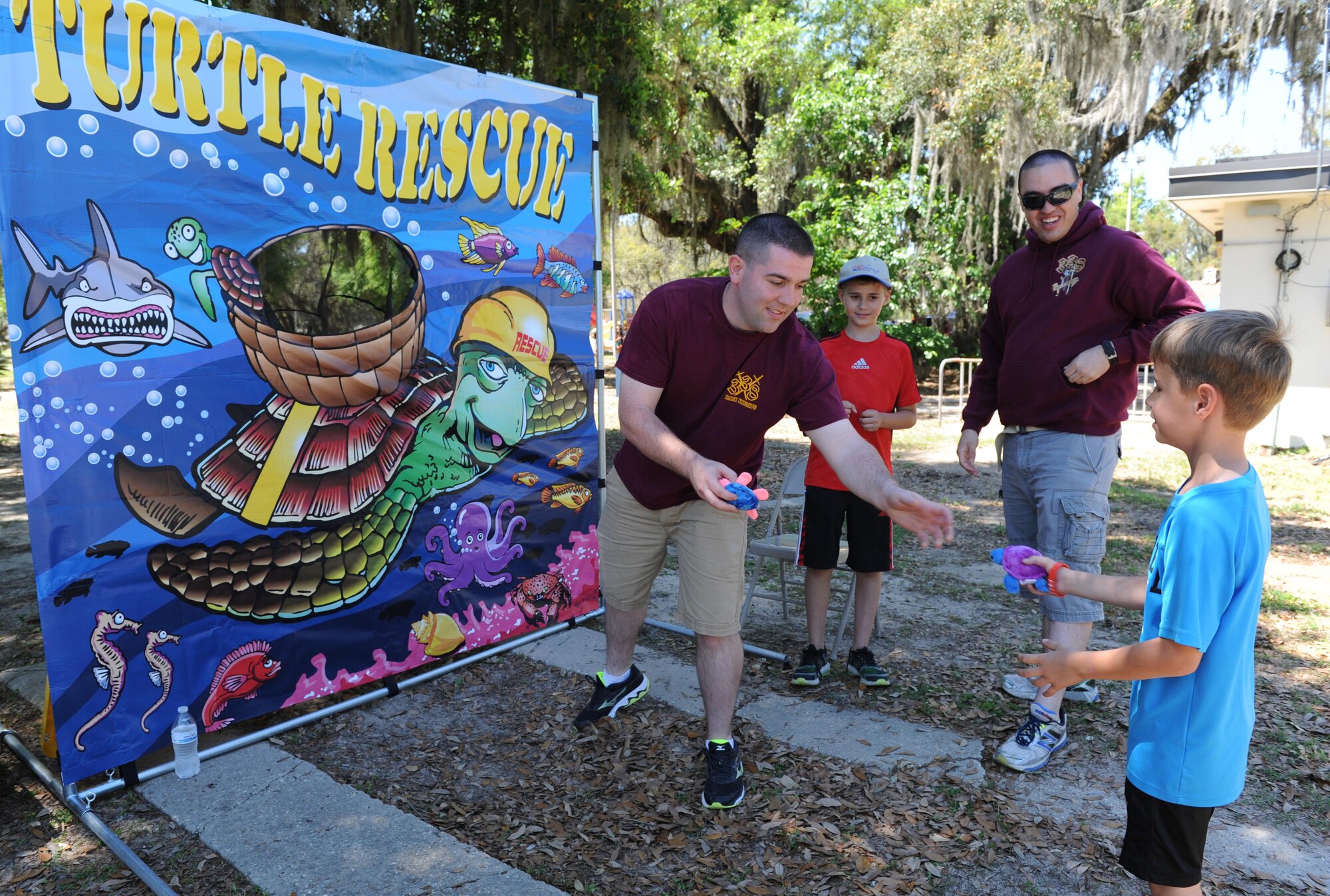 Airman 1st Class Daniel Shanks, 338th Training Squadron, assists Zachary Smith, son of Master Sgt. Sarah Smith, 81st Training Support Squadron curriculum developer, with a game of “Turtle Rescue” during Child Pride Day at marina park April 23, 2016, Keesler Air Force Base, Miss. Keesler families attended the annual event which featured activities, demonstrations and information on programs focused on care of military families. Child Pride Day was held in conjunction with the month of the military child. (U.S. Air Force photo by Kemberly Groue)