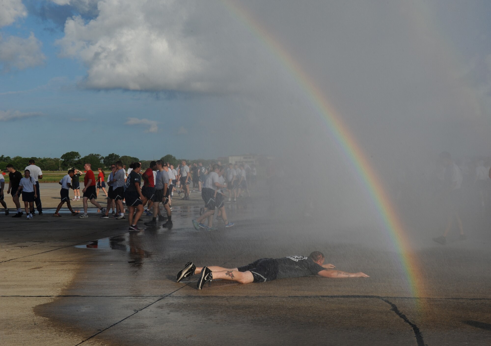 Staff Sgt. Jared Miller, 81st Security Forces Squadron combat arms instructor, relaxes below the mist and rainbow courtesy of the Keesler Fire Department following a 5K flightline run April 25, 2016, Keesler Air Force Base, Miss. The run was the kickoff event for a week full of activities supporting Wingman Week. (U.S. Air Force photo by Kemberly Groue)