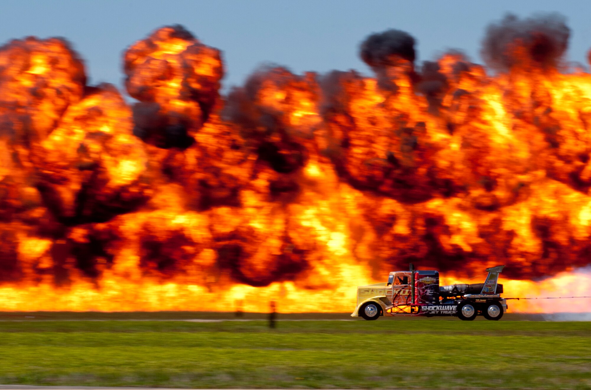 The SHOCKWAVE Jet Truck races in front of a pyrotechnic “wall of fire” during a performance during the AirPower over Hampton Roads Open House at Langley Air Force Base, Va., April 24, 2016. The truck uses more than 36,000 horsepower and holds the Guinness Book World Record for semi-truck speed at 376 miles-per-hour. (U.S. Air Force photo by Senior Airman R. Alex Durbin)