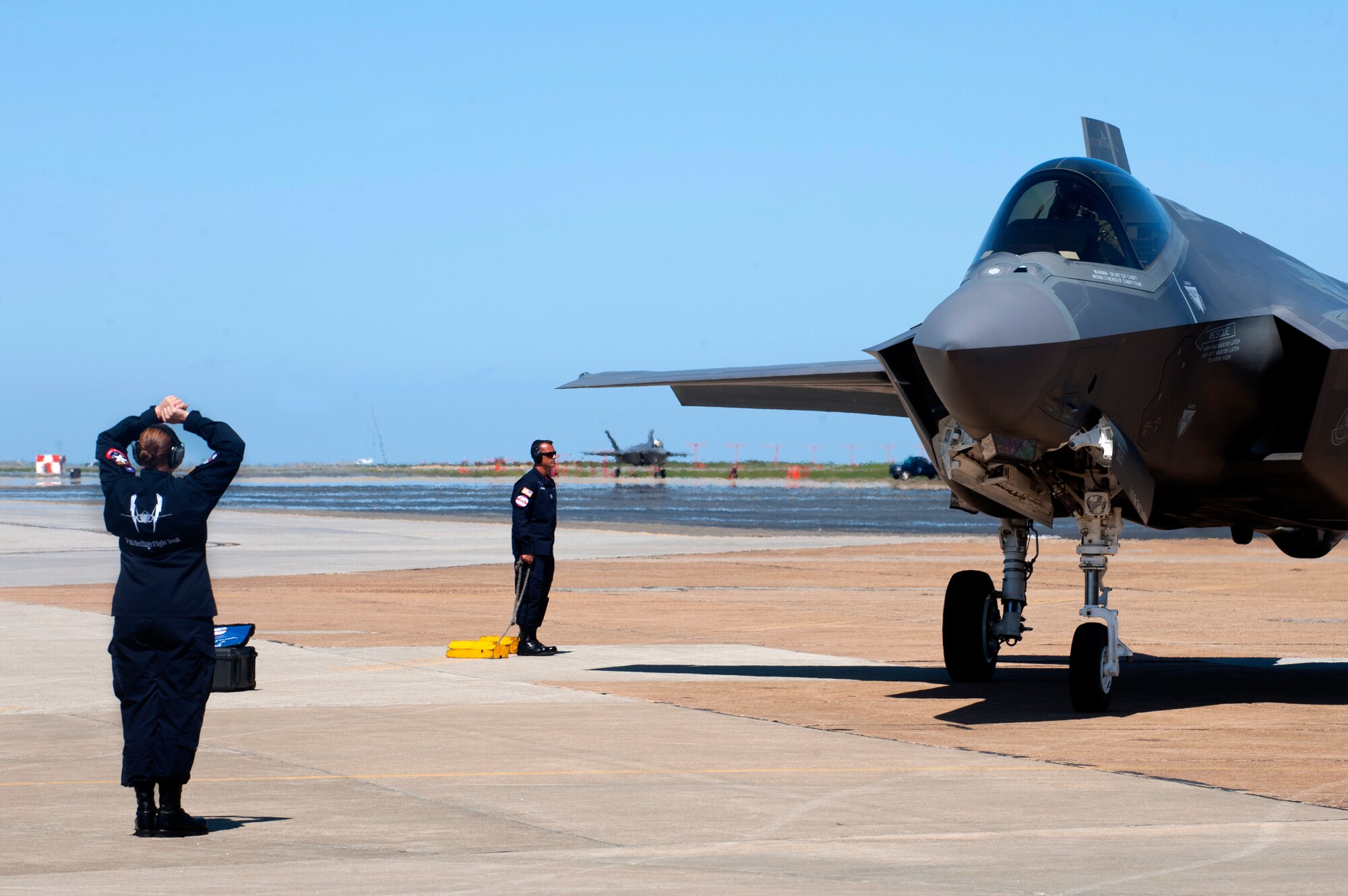 A U.S. Air Force F-35 Lightning II demonstration team member directs a team pilot during the AirPower over Hampton Roads Open House at Langley Air Force Base, Va., April 24, 2016. The pilot performed alongside and F-22 Raptor and a P-51 Mustang as part of the Heritage Flight Program, which showcases the evolution of air power by flying today's state-of-the-art fighter aircraft in close formation with vintage fighter aircraft.
(U.S. Air Force photo by Senior Airman R. Alex Durbin)
