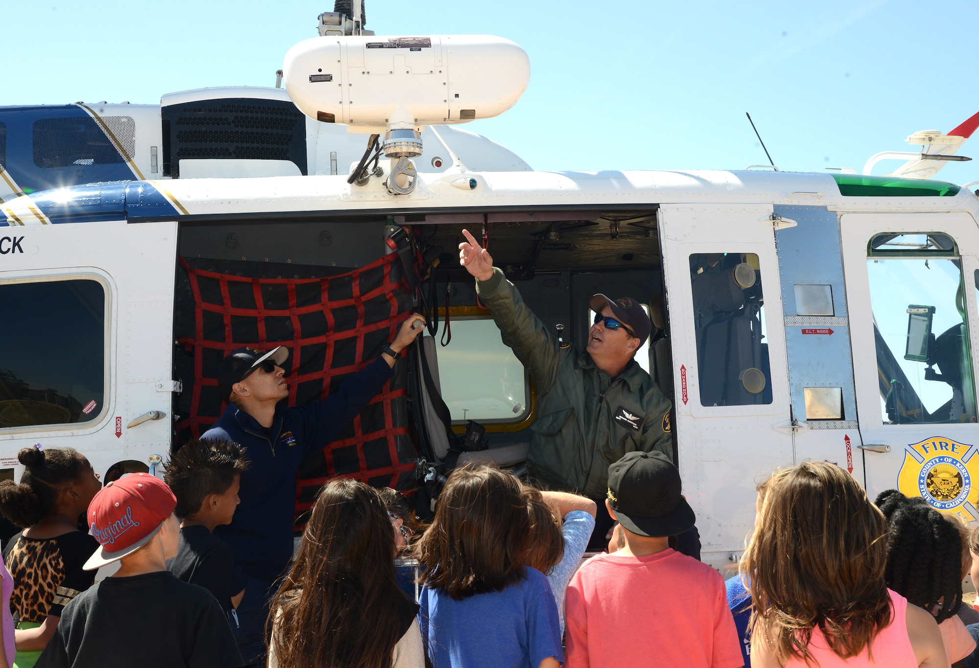 Kern County Fire Department captain Richard Anderson (right), with the help of crew member Martin Galvin, explains the workings of a helicopter rescue hoist to Edwards schoolchildren during Earth Day presentations at Bailey Elementary School Friday. According to Blake Burris, the aircraft’s pilot, the UH-1N “Huey” helicopter was originally a military aircraft during the Vietnam War era. It has since been modified with firefighting and rescue equipment for use by the Kern County Fire Department. (U.S. Air Force photo by Christopher Ball)
