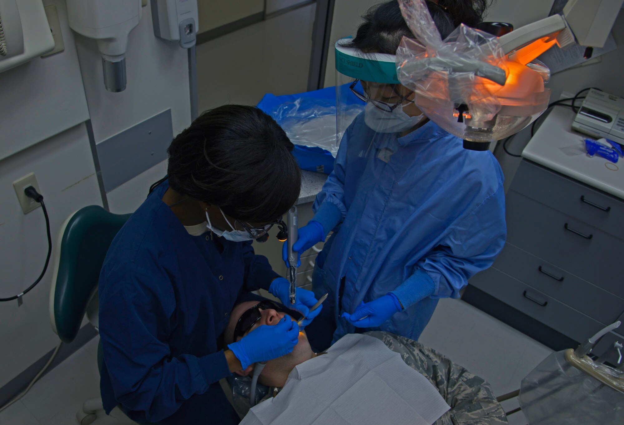 Maj. Teneshia Nelson-Hodges, 374th Dental Squadron general dentist receives help from Kaori Sashida, 374th DS dental assistant, to fix a tooth filling for Master Sgt. Daniel McDonald, 374th Surgical Operations Squadron, at Yokota Air Base, Japan, April 19, 2016. To effectively take care of the patients, the dental clinic has 18 dentists, 22 technicians and 24 civilians who work within seven sections: pediatrics, endodontics, prosthodontics, periodontics, orthodontics, oral surgery and radiology. (U.S. Air Force photo by Senior Airman David Owsianka/Released)