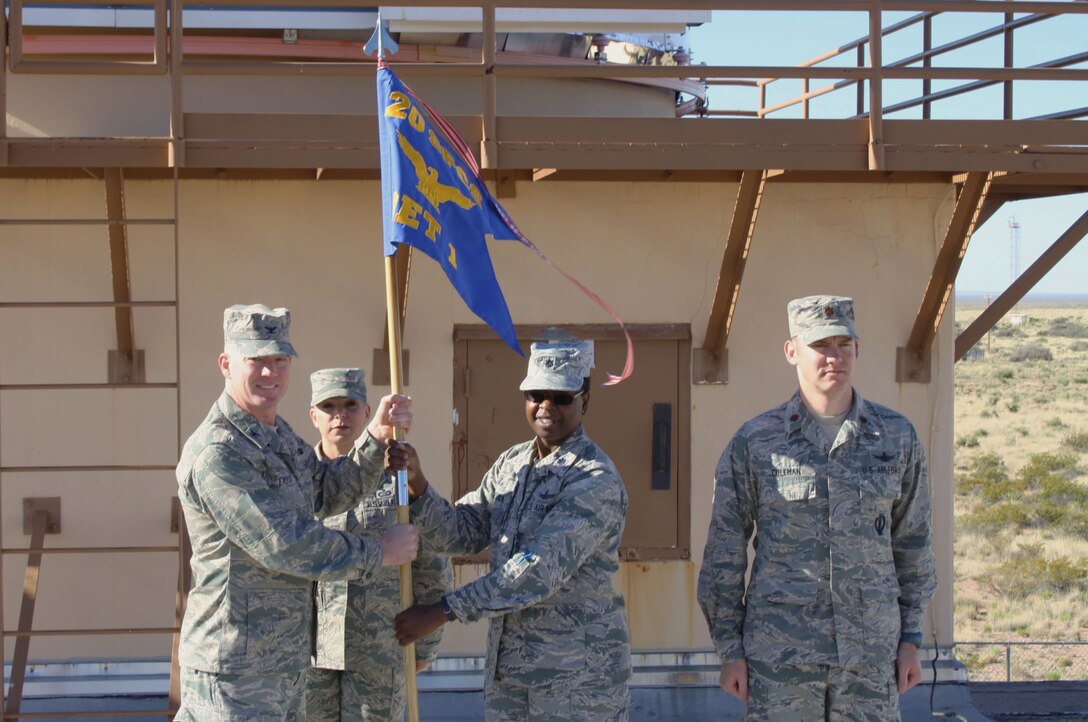 WHITE SANDS MISSILE RANGE, New Mexico – Col. Troy L. Endicott, commander, 21st Operations Group, left, passes the guidon to Lt. Col. Mafwa Kuvibidila, 20th Space Control Squadron commander during a redesignation ceremony April 20. Maj. Daniel Coleman, far right, 20th SPCS Detachment 1 commander and Chief Master Sgt. Kristine Jones, superintendent, 21st Operations Group, take part in the event marking the official move of three Ground-based Electro-Optical Deep Space Surveillance Systems detachments to the 20th SPCS from direct control of the 21st Operations Group. (Courtesy photo)