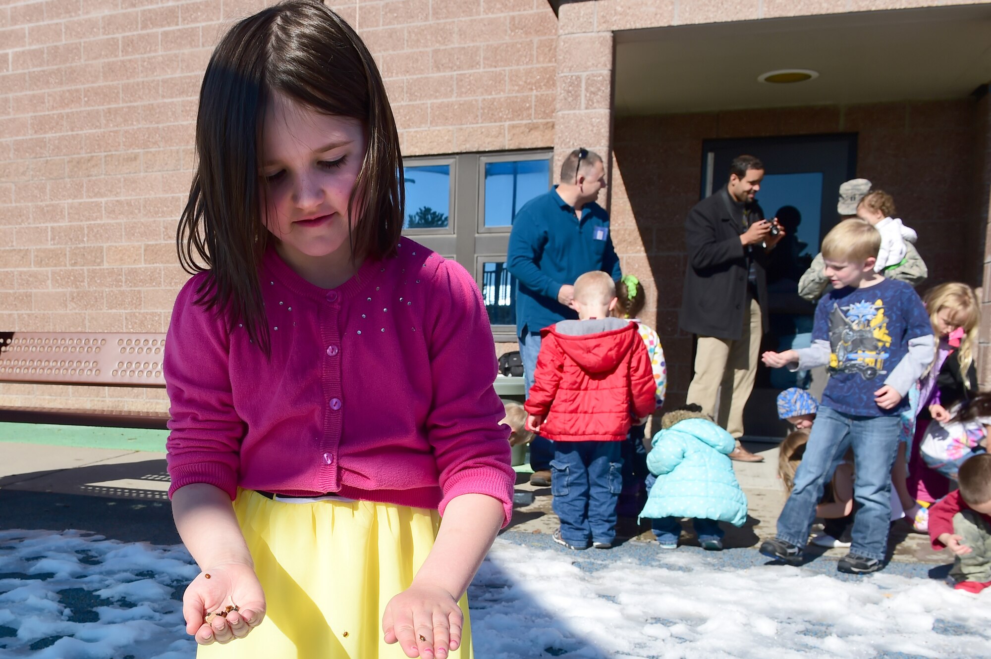 A girl from the Crested Butte Child Development Center stands with a handful of ladybugs April 22, 2016, on Buckley Air Force Base, Colo. Team Buckley honored Earth Day with the release of ladybugs and a tree planting ceremony. (U.S. Air Force photo by Airman 1st Class Luke W. Nowakowski/Released)