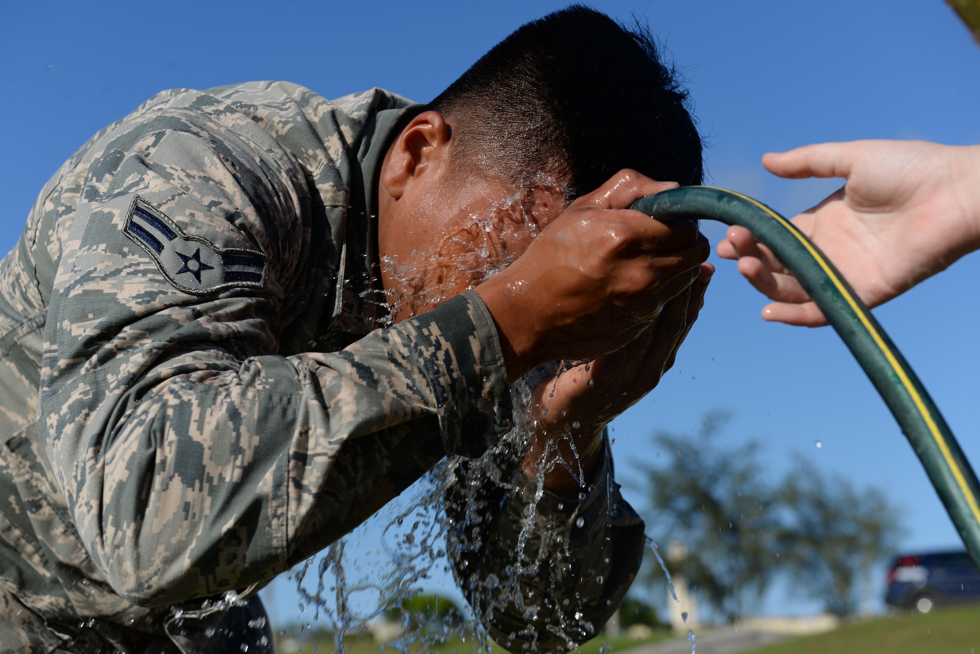 Airman 1st Class Andrew Smith, 36th Security Forces Squadron unit orientation training member, washes oleoresin capsicum spray off his face after completing an obstacle course March 25, 2016, at Andersen Air Force Base, Guam. SFS Airmen receive a dose of the spray during the training course to learn just how effective OC spray is and that they only need to use it in small amounts. (U.S. Air Force photo by Airman 1st Class Jacob Skovo) 
