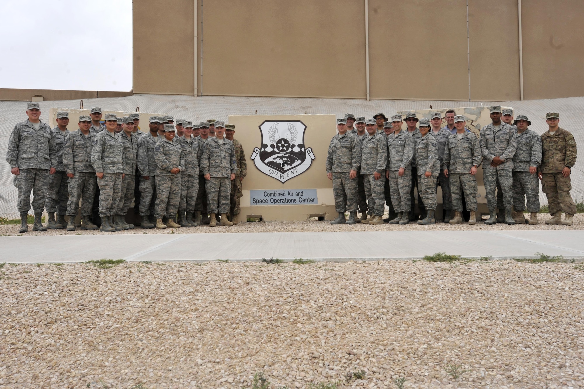 Members of the Air Forces Central Command Communications Directorate pose near a t-wall at Al Udeid Air Base, Qatar April 6. The directorate members, known as the "Six Shooters" are responsible for maintaining secure, reliable lines of communication across the AFCENT area of operations. (U.S. Army photo by Spc. Travis Terreo)