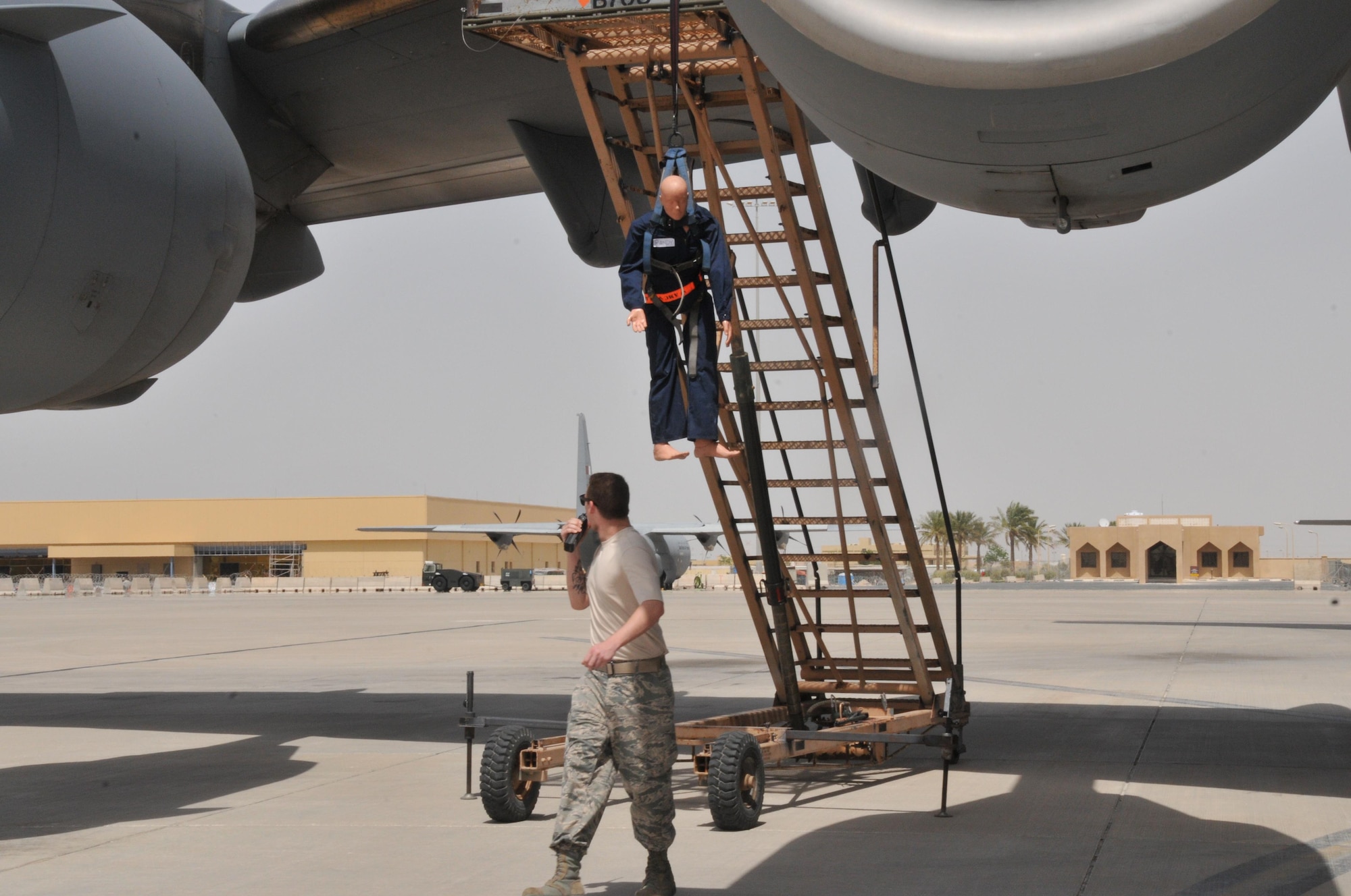 Members of the 8th Expeditionary Aircraft Maintenance Squadron conducted a fall-rescue exercise April 15 at Al Udeid Air Base, Qatar. Staff Sgt. Steven Sentner, 8th EAMS crew chief, calls the maintenance operations center for help, after seeing a “maintenance worker” suspended by a harness from an aircraft here. The exercise tested and validated the in-place plan to provide expedient care for the trapped member. (U.S. Air Force photo by Tech. Sgt. Terrica Y. Jones/Released)