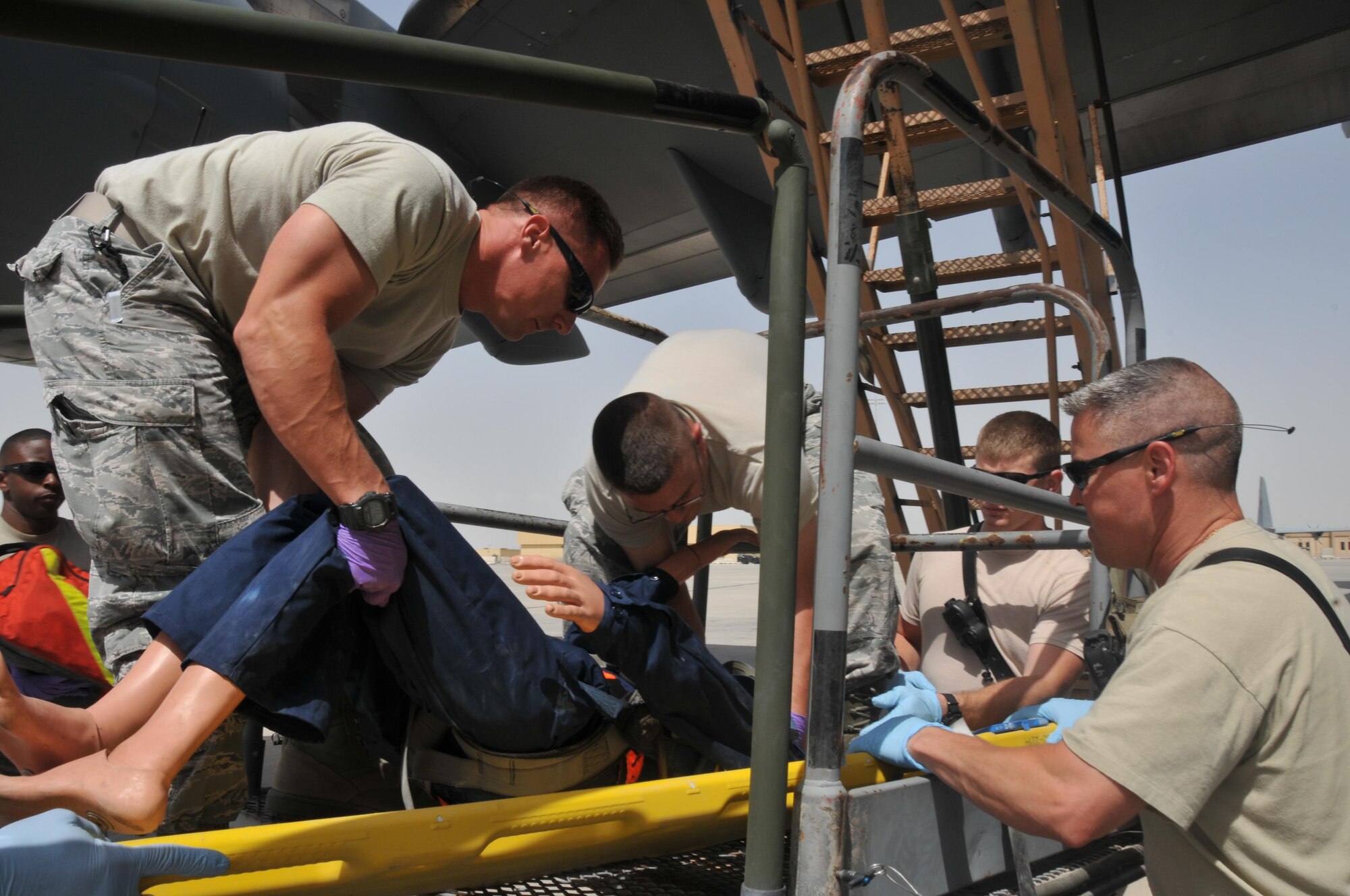 Members of the 379th Expeditionary Civil Engineer Squadron fire department prepare an injured “maintenance worker” for transport to the nearest medical facility, during a fall-rescue exercise April 15 at Al Udeid Air Base, Qatar. The scenario tested and validated procedures to provide expedient care for a member, who had been suspended from an aircraft for an undetermined amount of time. (U.S. Air Force photo by Tech. Sgt. Terrica Y. Jones/Released)