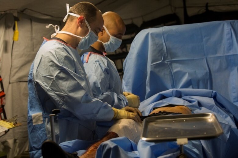 Sailors with 2nd Medical Battalion operate on the leg of a simulated shrapnel victim during the final scenario of Health Service Augmentation Program training at Camp Lejeune, N.C., April 22, 2016. The sailors were woken up at 0500 by the sounds of simulated artillery rounds and wounded service members. The sailors had to quickly assess the scene and provide medical attention to as many as ten different victims, all with various injuries.