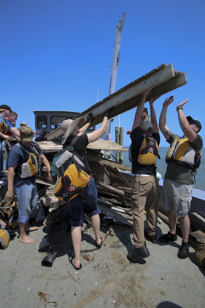 Marines from 2nd Radio Battalion and 2nd Law Enforcement Battalion hoist debris that they collected during the beach clean-up of Shackleford Banks Island April 21, 2016. The Marines picked up trash and debris to create a better environment for the wild horses that inhabit the island. (U.S. Marine Corps photo by Lance Cpl. Miranda Faughn/Released)