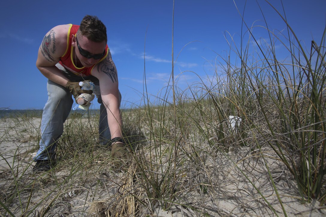 With two bottles in hand, Sgt. Ryan Stoddard, 2nd Radio Battalion picks up another, as part of the beach cleanup assisted by the National Park Service on Shackleford Banks Island April 21, 2016. Gunnery Sgt. Bernard Snyder with 2nd Law Enforcement Battalion brought together the Marines after being compelled by seeing the trash affecting the wildlife. (U.S. Marine Corps photo by Lance Cpl. Miranda Faughn/Released)