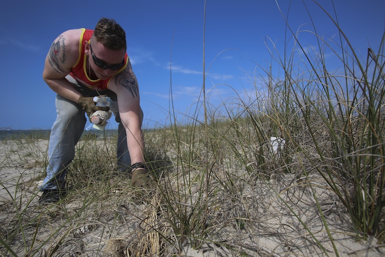 With two bottles in hand, Sgt. Ryan Stoddard, 2nd Radio Battalion picks up another, as part of the beach cleanup assisted by the National Park Service on Shackleford Banks Island April 21, 2016. Gunnery Sgt. Bernard Snyder with 2nd Law Enforcement Battalion brought together the Marines after being compelled by seeing the trash affecting the wildlife. (U.S. Marine Corps photo by Lance Cpl. Miranda Faughn/Released)