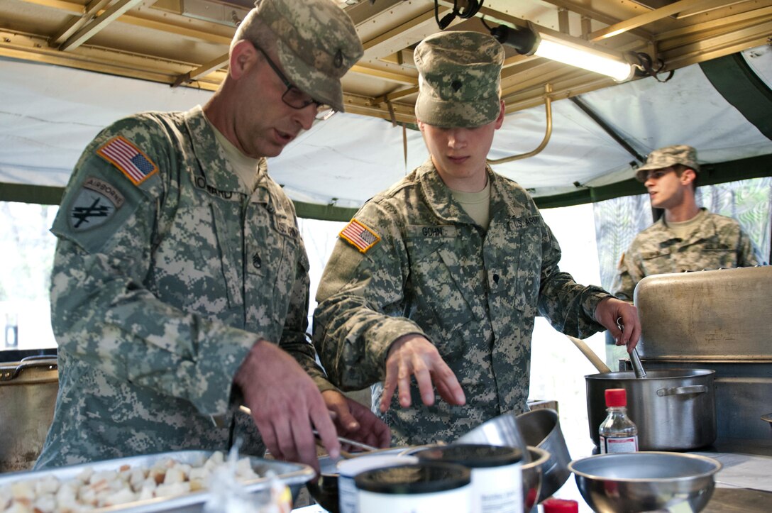 Spc. Austin Gohn, a food service specialist with the 733rd Transportation Company, middle, instructs Staff Sgt. Dan Howard, also with 733rd T.C., on what utensils to bring him during the annual Philip A. Connelly Award competition at Fort Indiantown Gap, Pa., April 23, 2016. (U.S. Army photo by Staff Sgt. Dalton Smith / Released)