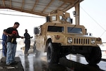 Ram Chhetri, a mechanic from Nepal, washes off an M1151 up-armored Humvee outside the 1st Battalion, 401st Army Field Support Brigade vehicle maintenance facility at Camp As Sayliyah, Qatar, Oct. 8. Ray Green, a mechanic from Charleston, S.C., supervises from behind the vehicle. Shipped from Iraq, ITT-contracted mechanics finished retrofitting the vehicle to Fragmentation Kit Seven configurations, upgrading it from FRAG-5.