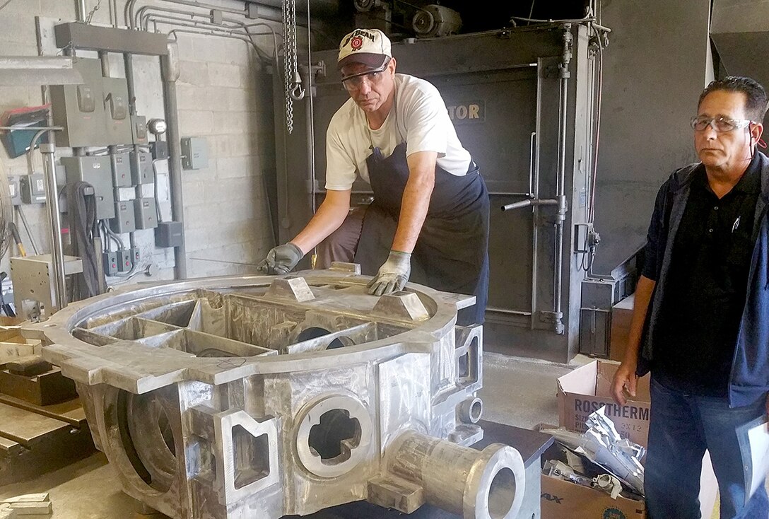 Workers at Danko Arlington, Inc., inspect a newly finished part for the Navy’s Aegis Combat System recently removed from its mold.