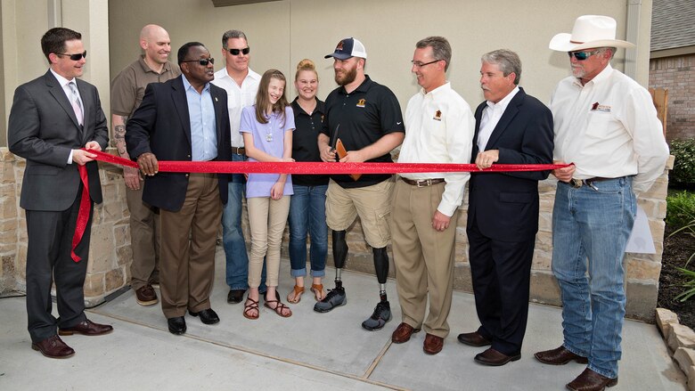 U.S. Marine Corps Cpl. Jonathan Dowdell (center), holds a combat knife in his hands to begin the ribbon cutting ceremony as part of a special welcome home ceremony in League City, Texas, April 14, 2016. The home dedication marks Operation FINALLY HOME’s 100th dedication for a deserving veteran or surviving spouse.