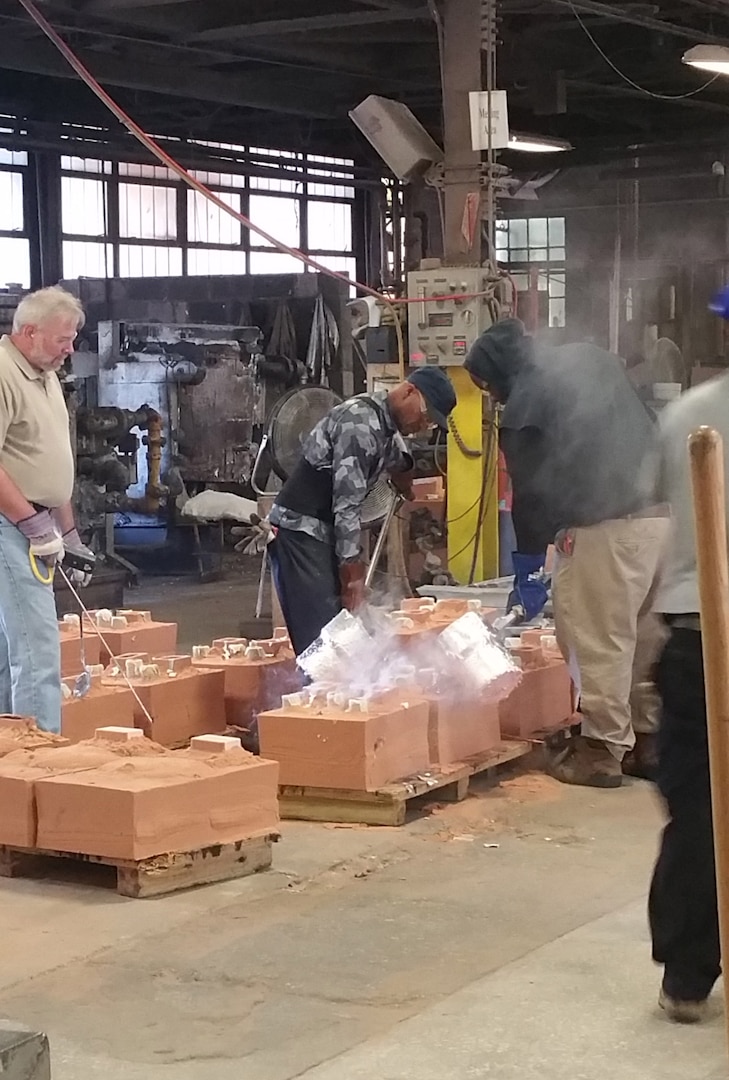 Workers at Danko Arlington, Inc., a casting facility in Baltimore, Maryland, pour molten metal into a sand casting mold. Once cooled, the part will be removed and the sand recycled for use in another project.