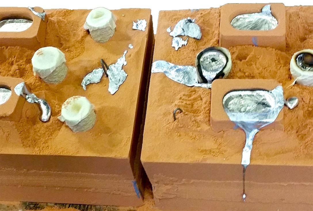 Molten metal cools inside the sand casting mold after being poured. Once the metal has cooled, workers break the mold and remove the part for inspection and further processing.
