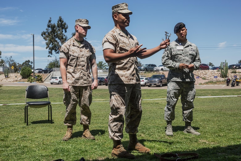 A student, left, and two instructors with Naval Consolidated Brig Miramar demonstrate how to use several restraints during a Basic Brig Escort course aboard Marine Corps Air Station Miramar, Calif., April 19. The instructors with Naval Consolidated Brig Miramar certified 60 service members as basic escorts which will enable them to conduct prisoner escorts aboard MCAS Miramar and Marine Corps Base Camp Pendleton.  (U.S. Marine Corps photo by Sgt. Lillian Stephens/Released)