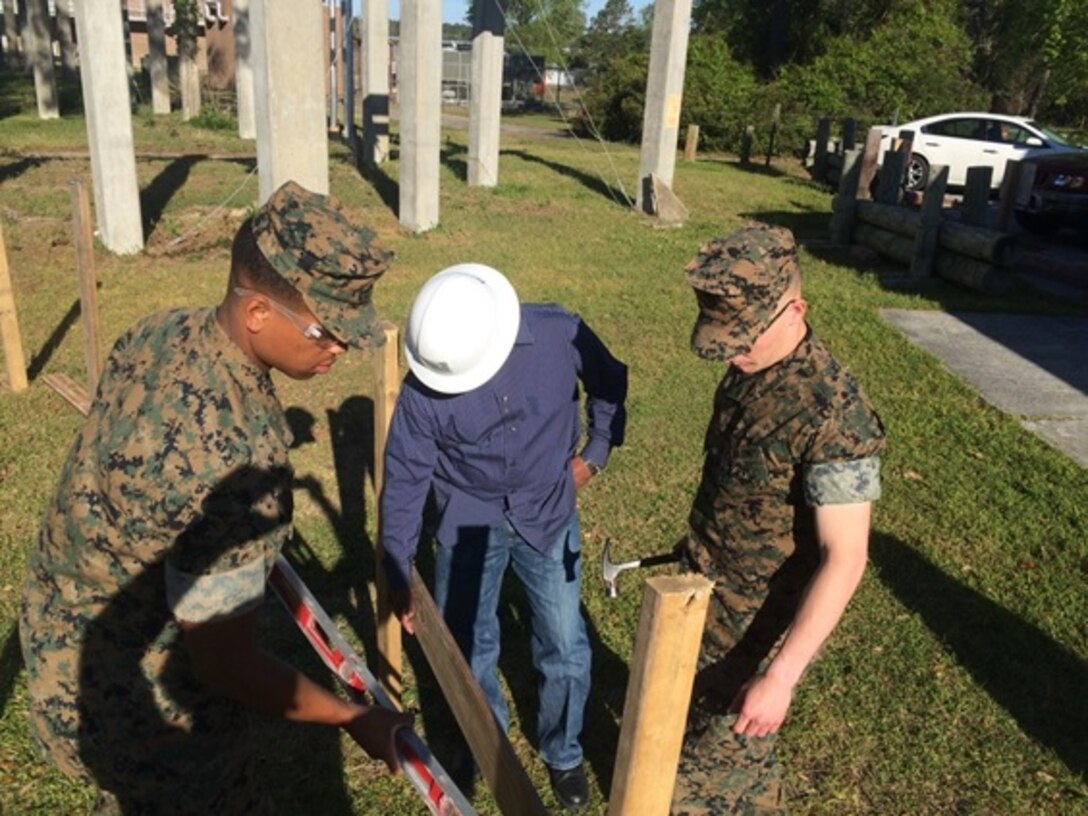 On April 18, 2016 Mr. Jose Velasquez (middle), an instructor with Combat Engineer Instruction Company; assists Second Lieutenant Aaron Graham (left) and First Lieutenant Jonathan Lanning Keller (right), Marines attached to Combat Engineer Officer course 5-16 (CEO 5-16); in leveling a board in their foundation as part of a vertical construction practical application. Leveling the frame ensures the foundation of the building is level.
