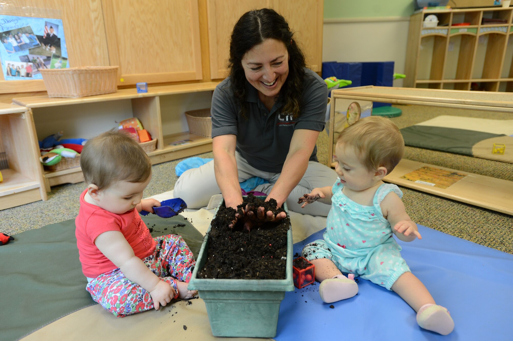 Daisy Gonzalez, 20th Force Support Squadron Chandler Cornell Child Development Center infant program lead, plants seeds in potting soil with Team Shaw children at Shaw Air Force Base, S.C., April 22, 2016. The 20th Force Support Squadron Child and Youth Services Parent Advisory Committee and CDC staff teamed up to provide nature-themed activities for children in celebration of Earth Day. (U.S. Air Force photo by Senior Airman Zade Vadnais)