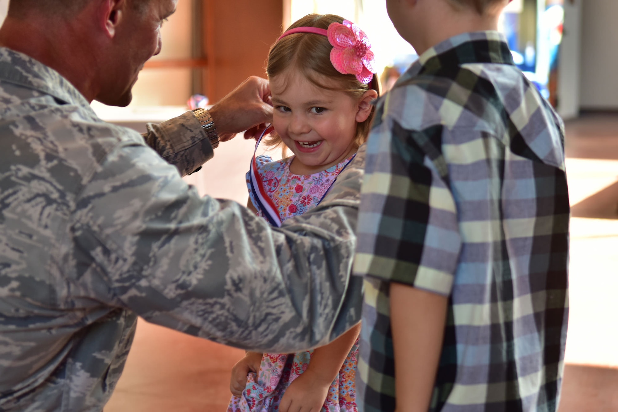 Colonel Charles Velino, commander, 15th Operations Group, places a medallion on the Jewel Keiter during the Homefront Heroes ceremony, held April 20, 2016, at the Hickam Military and Family Support Center. Homefront Heroes is a yearly event to recognize children whose parents are currently serving in a deployed environment, or who are frequently TDY. The event is intended to highlight the sacrifices the children make, and the challenges they face when their loved one is away from home. (U.S. Air Force photo by Staff Sgt. Christopher Stoltz)