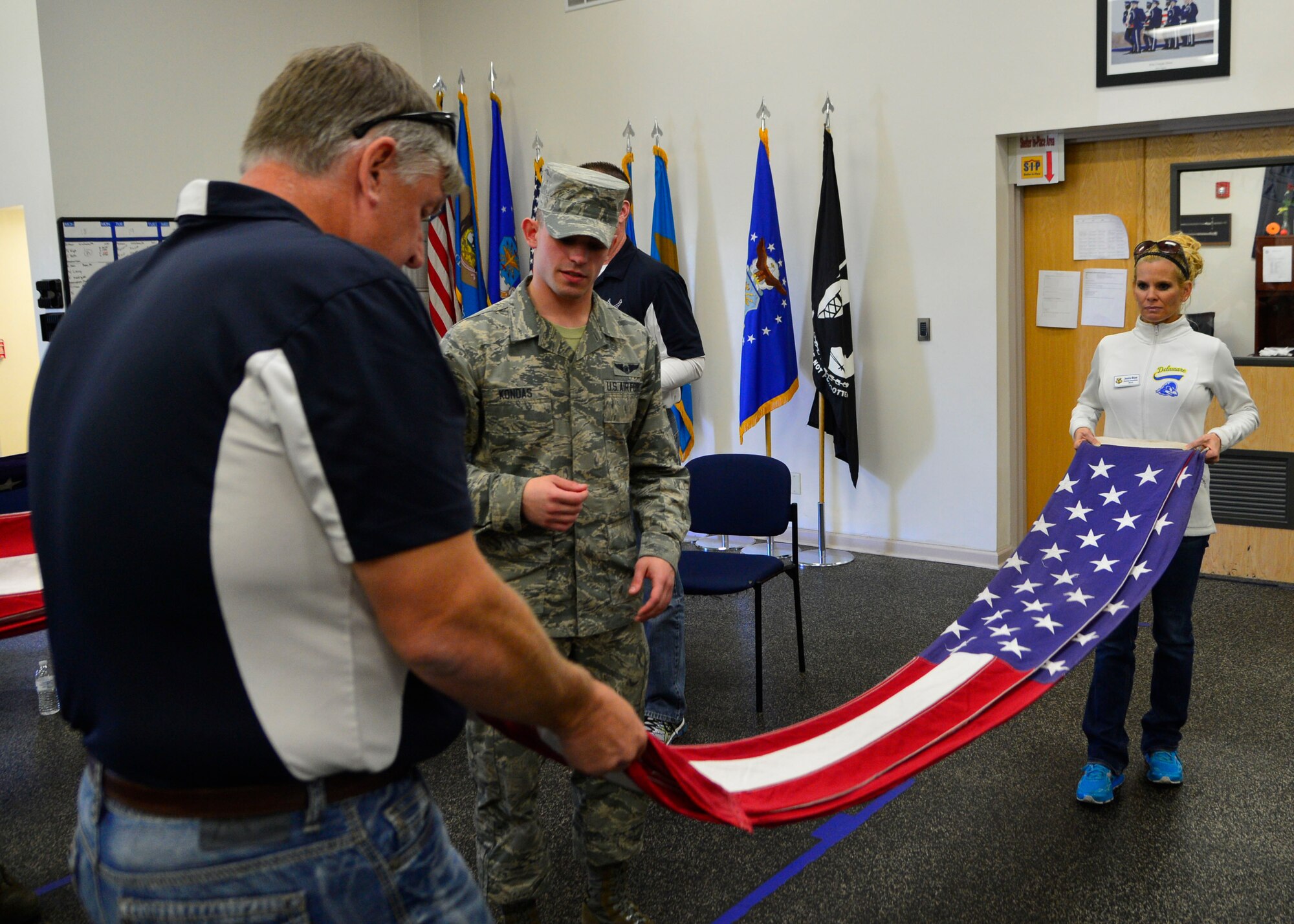 Senior Airman Kyle Kondas, Dover Air Force Base Honor Guard member, helps two Team Dover Honorary Commanders fold a flag during a tour of the 436th Mission Support Group April 20, 2016, at Dover Air Force Base, Del. The honorary commanders competed in teams of two to see who could fold the flag the best while touring the base Honor Guard facility. (U.S. Air Force photo/Senior Airman William Johnson)