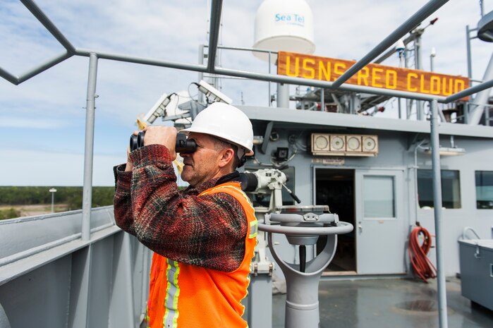 Phil Crisfield, 3rd mate aboard the U.S. Naval Ship Red Cloud, looks through a pair of binoculars April 18, 2016, at Joint Base Charleston, S.C. – Weapons Station. Members from the Army Strategic Logistics Activity Charleston and the 841st Transportation Battalion staged, processed and configured 1,300 pieces of equipment to support USNS Red Cloud’s prepositioned ship mission. (U.S. Air Force photo/Staff Sgt. Jared Trimarchi) 