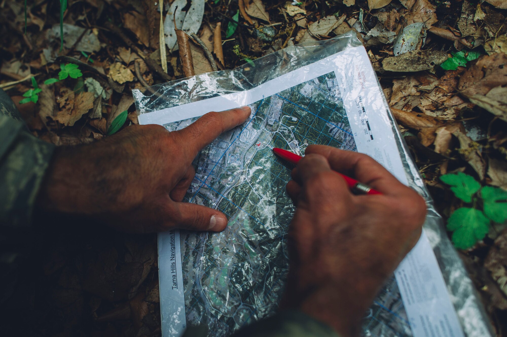 Lt. Col. Troy Saechao, 374th Operations Support Squadron director of operations, examines a map during combat survival training at Tama Hills Recreation Area, Japan, April 21, 2016. The SERE training uses realistic wilderness situations to teach students the importance, difficulty and technique of navigation using simple instruments. (U.S. Air Force photo by Senior Airman Delano Scott/Released)