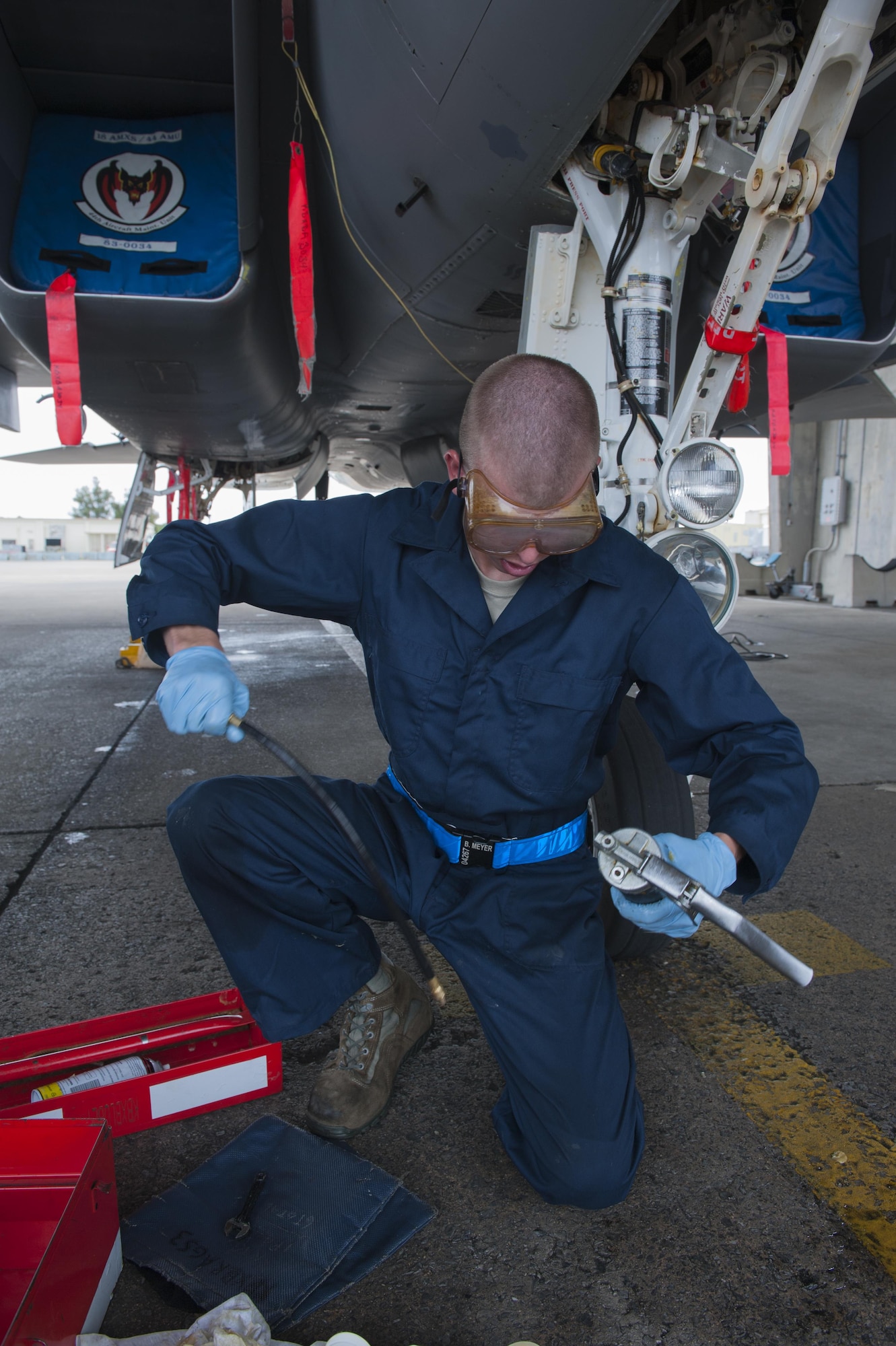 U.S. Air Force Brandon Meyer, 44th Aircraft Maintenance Unit crew chief, sets up a lubricant pressure gun for applying lubricant to the moving parts and bearings of the aircraft to minimize any down time, April 26, 2016, at Kadena Air Base Japan. Each F-15C Eagle must be lubricated after each monthly cleaning, which removes most of the lubricant. (U.S. Air Force photo by Airman Zackary A. Henry)