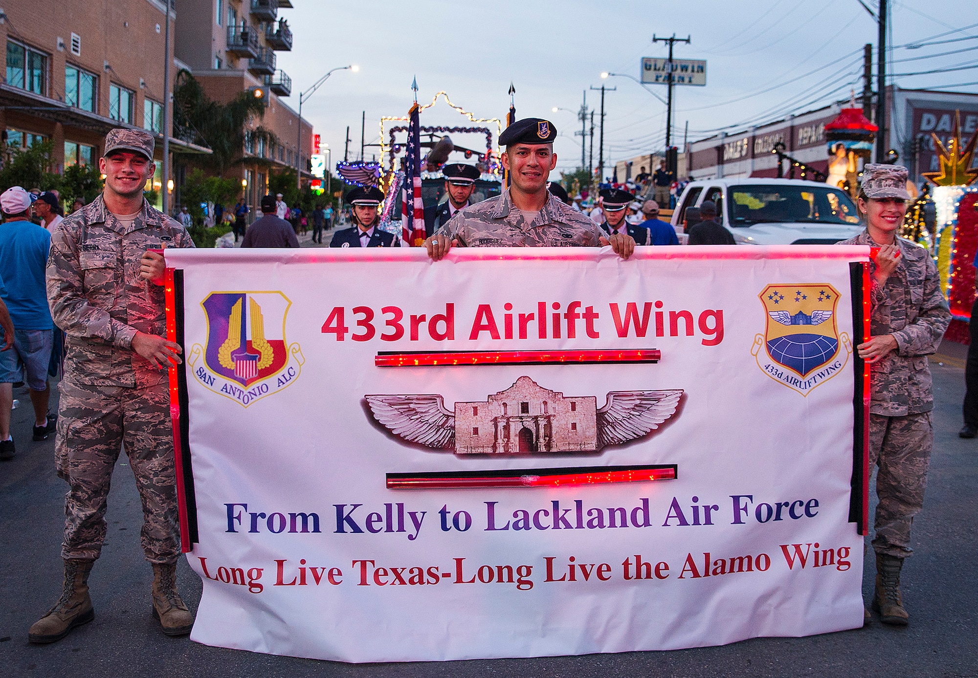 Airman 1st Class Richard Serna, 433rd Logistics Readiness Squadron vehicle operations, Staff Sgt. Pedro Rodriguez, 433rd Security Forces Squadron fire team member, and Senior Airman Tequina Fernandez, 433rd Aerospace Medicine Squadron dental assistant, carry the 433rd Airlift Wing banner during the Fiesta Flambeau parade April 23, 2016. The Fiesta Flambeau parade is one of the largest illuminated parades in the world, with over 750,000 spectators and 1.5 million television viewers.  (U.S. Air Force photo by Benjamin Faske) (released)