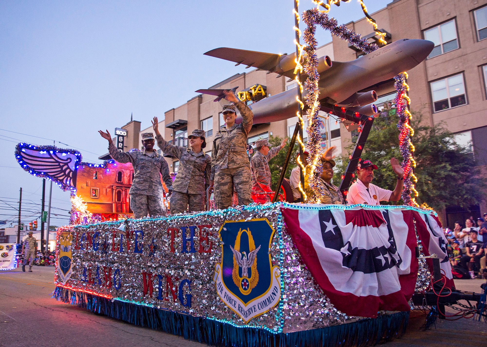 Airmen from the 433rd Airlift Wing wave to the crowd as they  participate in the Fiesta Flambeau parade April 23, 2016. The Fiesta Flambeau parade is one of the largest illuminated parades in the world, with over 750,000 spectators and 1.5 million television viewers. (U.S. Air Force photo by Benjamin Faske) (released)