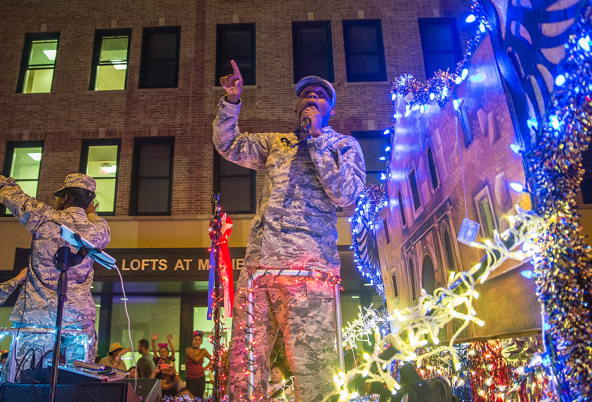 Tech. Sgt. Robert Carter, 531st Intelligence Squadron section chief knowledge operations, sings to the crowd as the 433rd Airlift Wing float during the Fiesta Flambeau parade April 23, 2016. The Fiesta Flambeau parade is one of the largest illuminated parades in the world, with over 750,000 spectators and 1.5 million television viewers. (U.S. Air Force photo by Benjamin Faske) (released)