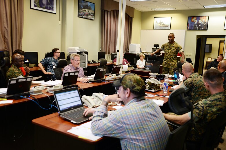 Marine Corps Logistics Base Albany staff members debrief the senior watch officer during Exercise Black Swan 2016, here, April 13.