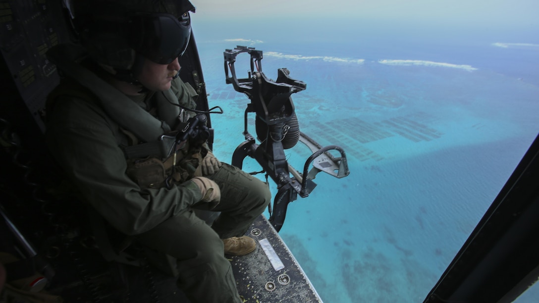 Sgt. Jeffrey L. Allen scopes out the terrain from his seat in a UH-1Y Huey at Marine Corps Air Station Futenma, Okinawa, Japan, April 8, 2016,. Allen, along with other crew chiefs and aircraft maintainers, may work up to 16 hours a day performing maintenance and checks on aircraft to ensure safe missions. Allen, from Ennis, Texas, is with Marine Light Attack Helicopter Squadron 167, currently supporting Marine Aircraft Group 36, 1st Marine Aircraft Wing, III Marine Expeditionary Force, under the unit deployment program.