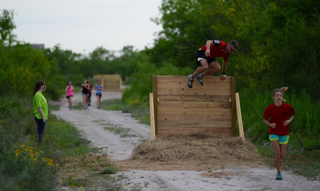 Lt. Col. Gregory Soderstrom, 47th Student Squadron commander, second to right, climbs over an obstacle during the run portion at the Adventure Race on Laughlin Air Force Base, Texas, April 23, 2016. The Laughlin Adventure Race began in 2004 and has grown into a major event for the Del Rio and Laughlin communities. More than 5,000 people have competed in the race across Val Verde County. (U.S. Air Force photo by Senior Airman Ariel D. Partlow)
