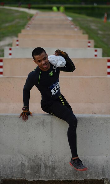 Airman 1st Class Omari Thomas, 47th Comptroller Squadron financial services technician, climbs over a hurdle during the run portion of the Adventure Race on Laughlin Air Force Base, Texas, April 23, 2016. Thomas competed individually in the “Insane” category, completing all activities alone in three hours, nine minutes and 17 seconds. (U.S. Air Force photo by Senior Airman Ariel D. Partlow)