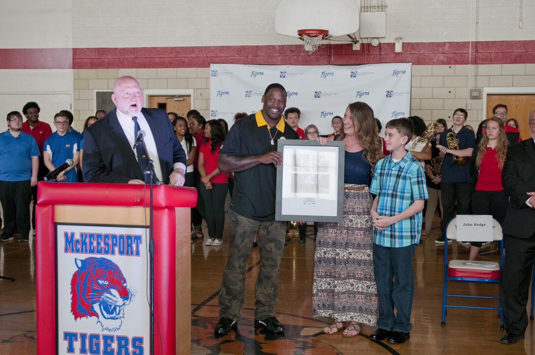 Arthur Moats, Pittsburgh Steelers linebacker, presents a collage of photos to Staff Sgt. Michelle Satterfield, with the 14th Quartermaster Detachment, during a ceremony for Satterfield in McKeesport, Pa., April 25, 2016. Satterfield is receiving a house built by the students of the McKeesport Area High School and Stephen Siller Tunnel to Towers Foundation for all of the volunteer work she has done in the past years. (U.S. Army photo by Staff Sgt. Dalton Smith / Released)