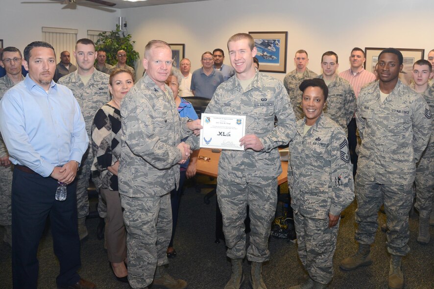 Airman 1st Class Tyler Troge, 47th Contracting Flight contract specialist, accepts the “XLer of the Week” award from Col. Darrell Judy, left, 47th Flying Training Wing vice commander, and Chief Master Sgt. Erica Shipp, right, 47th Mission Support Group superintendent, here, April 20, 2016. The XLer is a weekly award chosen by wing leadership and is presented to those who consistently make outstanding contributions to their unit and Laughlin. (U.S. Air Force photo by Airman 1st Class Brandon May)