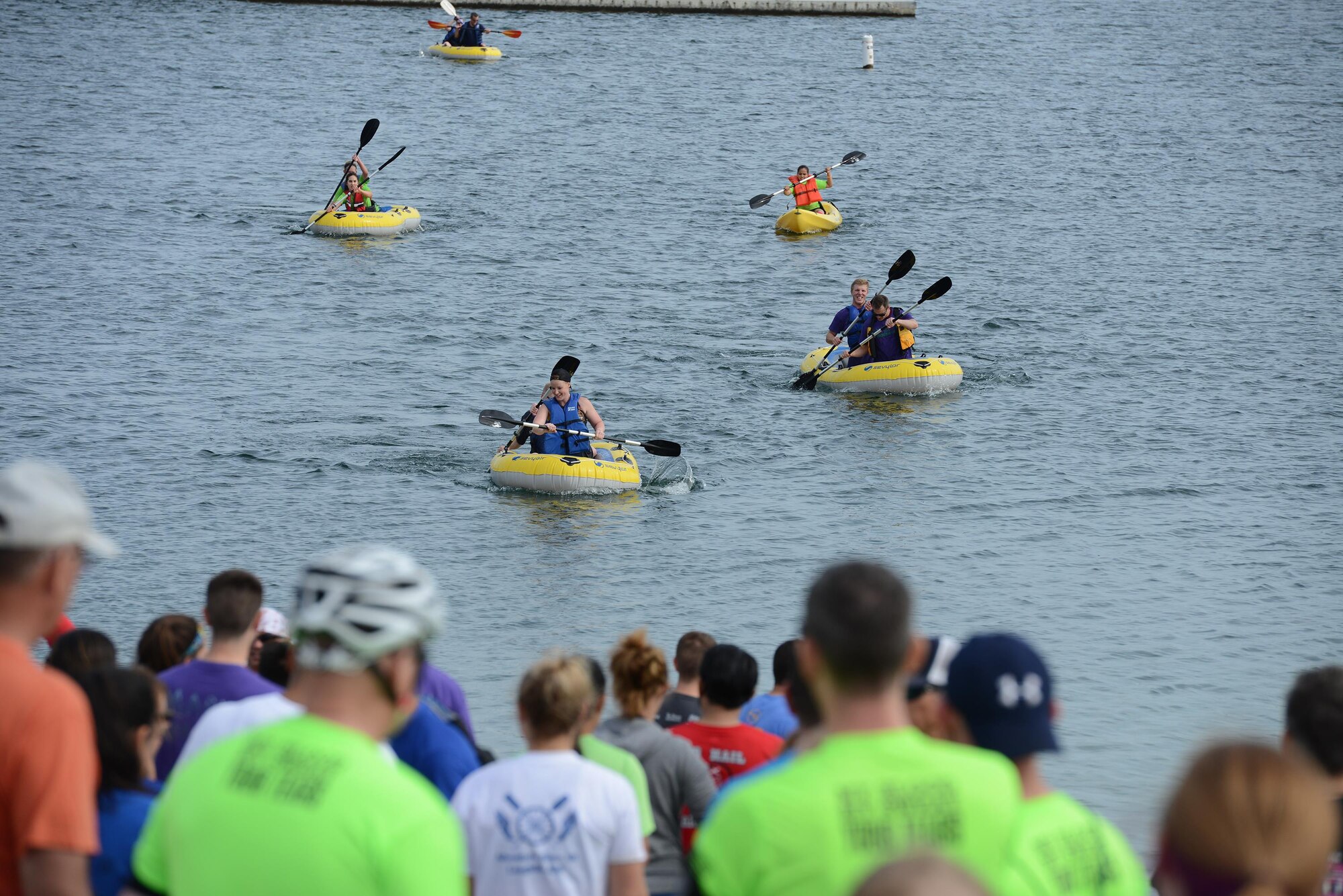 Onlookers watch Adventure Race XII participants finish the one-mile rafting portion of the race at Laughlin Southwinds Marina, Texas, April 23, 2016. Rafting was the final portion of the 28-mile race that was superseded by a 3-plus-mile run, six-foot tall wall climbs, a mud filled low-crawl, a concrete barrier hurdle and a 23- mile bike ride. (U.S. Air Force photo by Airman 1st Class Brandon May)