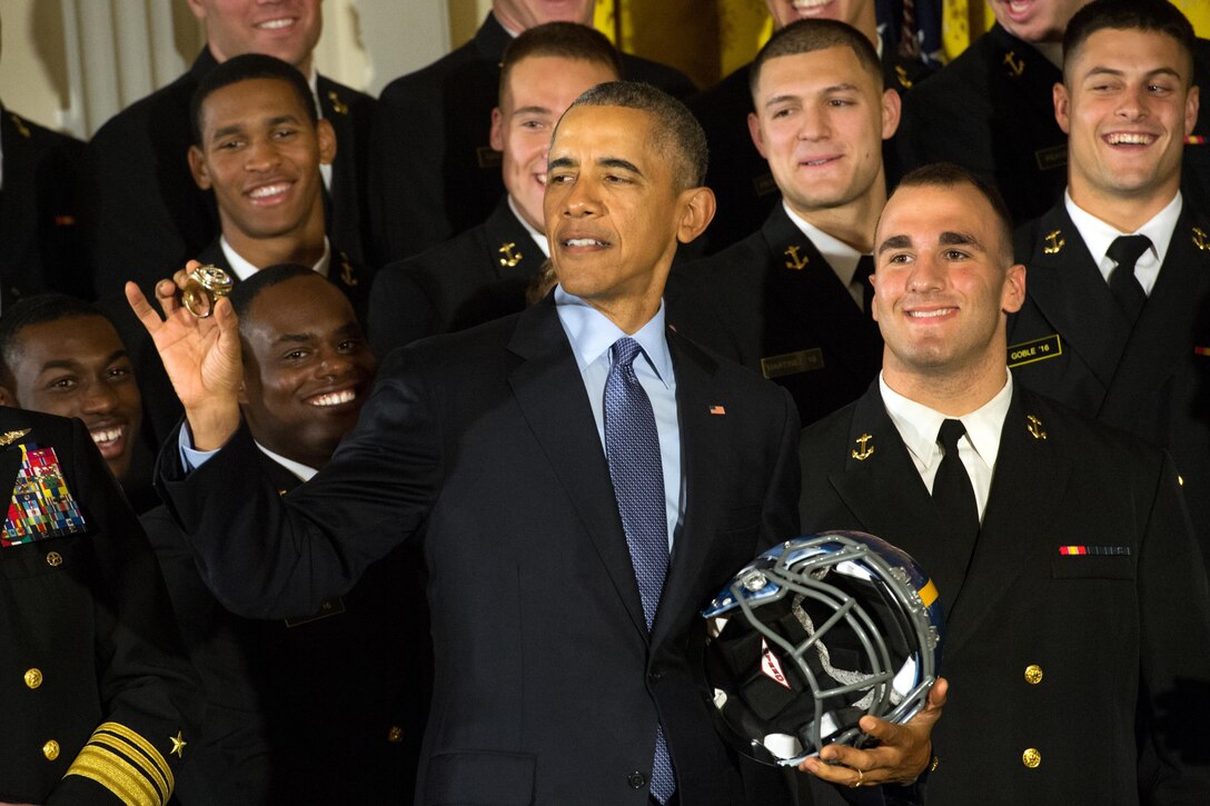 President Barack Obama holds a U.S. Naval Academy football helmet and inspects a team ring he received after awarding the Commander in Chief's Trophy to the team at the White House in Washington, D.C., April 27, 2016. DoD photo by EJ Hersom