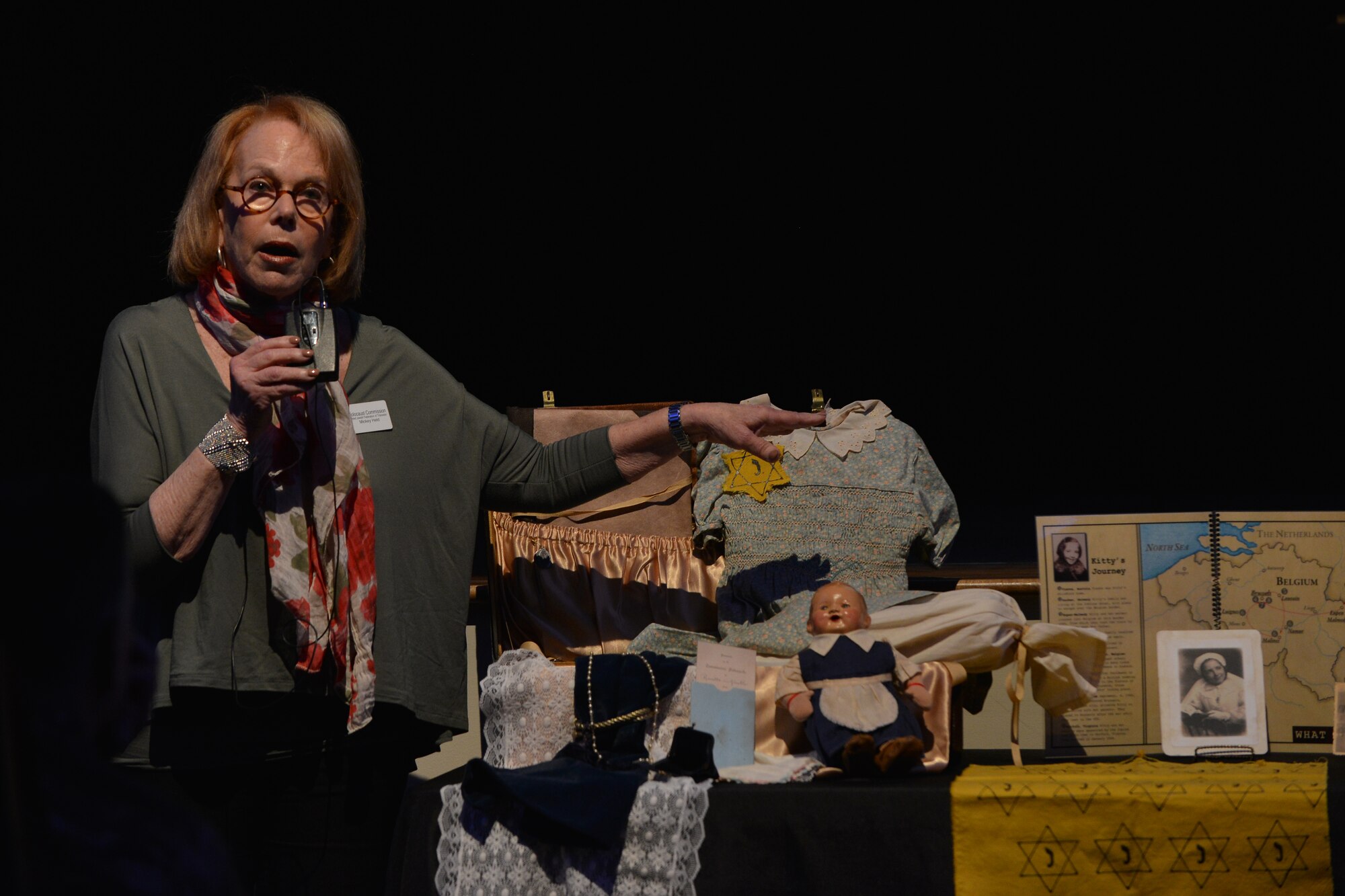 Mickey Held, holocaust commission member from the United Jewish Federation of Tidewater, shares with attendees at the Holocaust Days of Remembrance ceremony what Jewish refugees carried as they fled German occupied countries in WWII at Fort Eustis, Va., April 20, 2016. Joint Base Langley-Eustis held the ceremony to raise awareness of what humanity has been capable of in the past to prevent mistakes in the future. (U.S. Air Force photo by Staff Sgt. Natasha Stannard) 